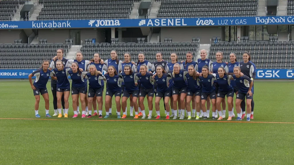 Equipo femenino de la Real Sociedad en su estadio, con publicidad de ASENEL